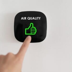 Hand pressing a button showing good air quality with a thumbs-up icon.
